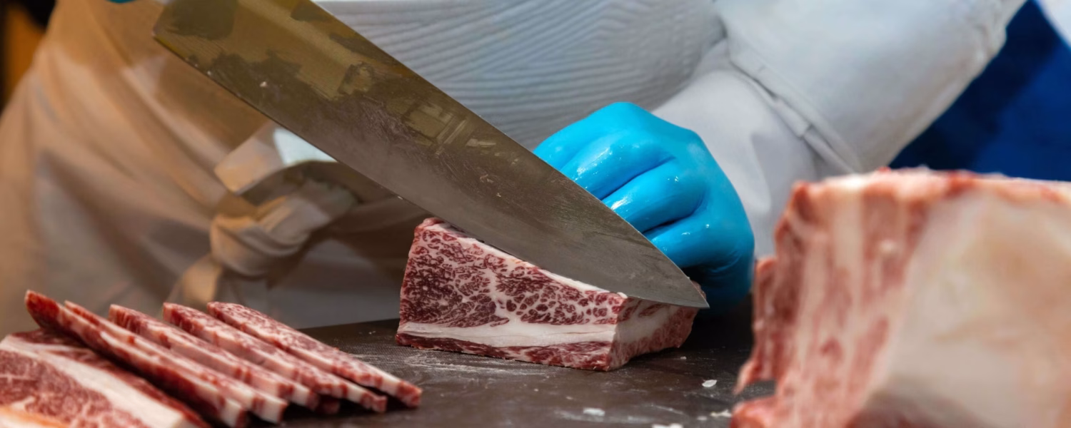 butcher cutting and preparing marbled wagyu beef
